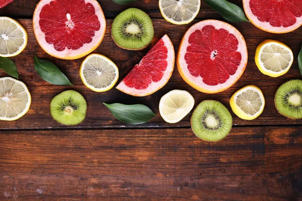 Zralé plátky citronu, kiwi a grapefruity na dřevěné pozadí — Stock fotografie