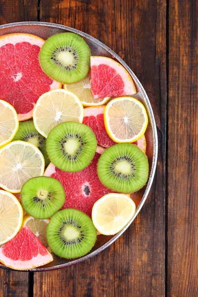 Fette mature limone, kiwi e pompelmo su vassoio su fondo di legno — Foto Stock