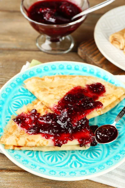 Deliciosos panqueques con mermelada de bayas en plato sobre fondo de madera — Foto de Stock