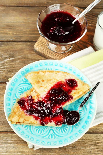 Placa de deliciosos panqueques con mermelada de bayas en plato sobre fondo de madera — Foto de Stock