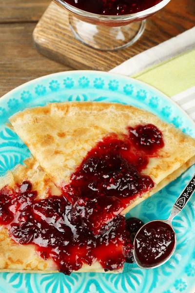 Placa de deliciosos panqueques con mermelada de bayas en plato sobre fondo de madera — Foto de Stock