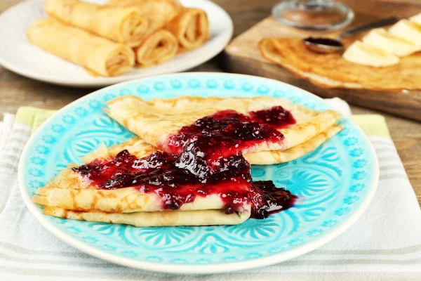 Panquecas deliciosas com geléia de baga e bananas em placas no fundo de madeira — Fotografia de Stock