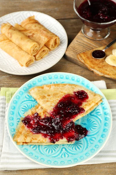 Delicious pancakes with berry jam  and bananas on plates on wooden background — Stock Photo, Image