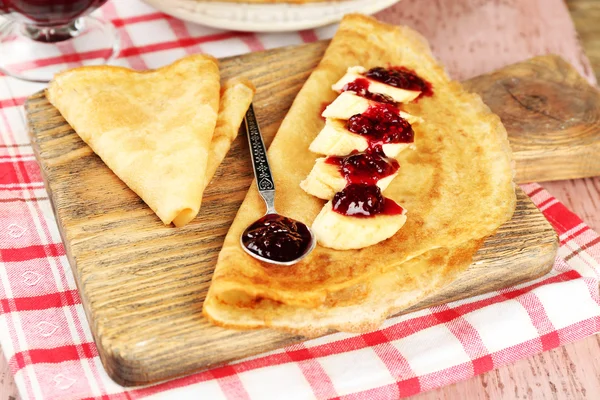 Heerlijke pannenkoeken met jam van de Bes en bananen op houten bord, op houten achtergrond — Stockfoto