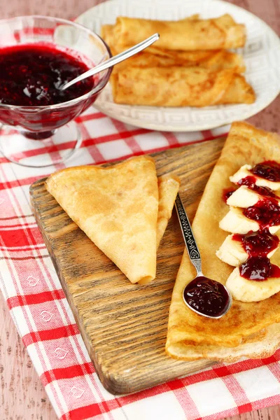 Heerlijke pannenkoeken met jam van de Bes en bananen op houten bord, op houten achtergrond — Stockfoto