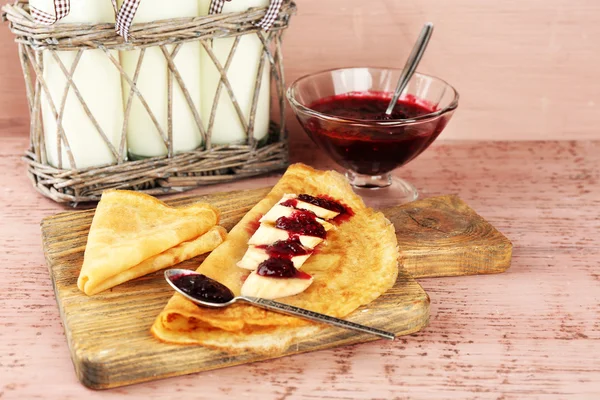 Delicious pannenkoeken met jam en bananen en melk flessen op houten achtergrond berry — Stockfoto