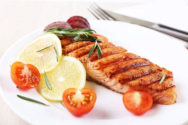 Salmón a la parrilla y verduras en plato sobre fondo de madera — Foto de Stock