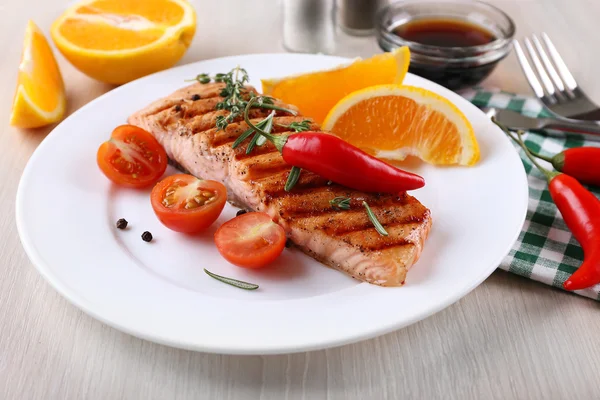 Salmão grelhado e legumes no prato em fundo de madeira — Fotografia de Stock