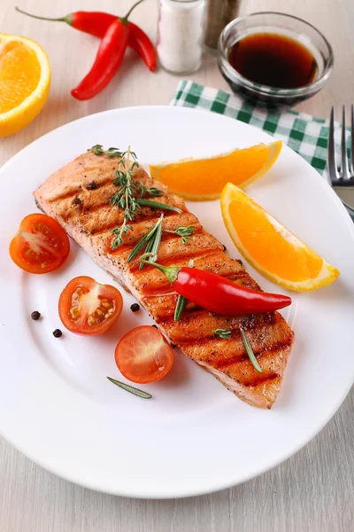 Grilled salmon and vegetables on plate on wooden background — Stock Photo, Image