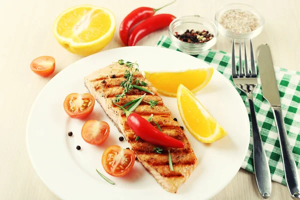 Salmão grelhado e legumes no prato em fundo de madeira — Fotografia de Stock