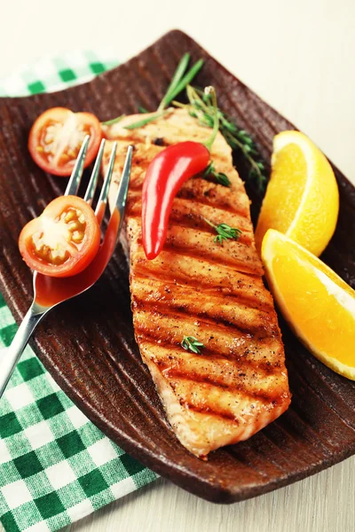 Гриль лосось и овощи на тарелке на деревянном фоне — стоковое фото