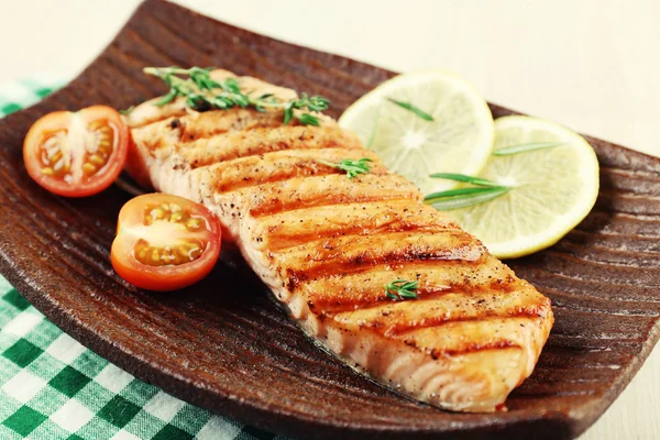 Grilled salmon and vegetables on plate on wooden background — Stock Photo, Image
