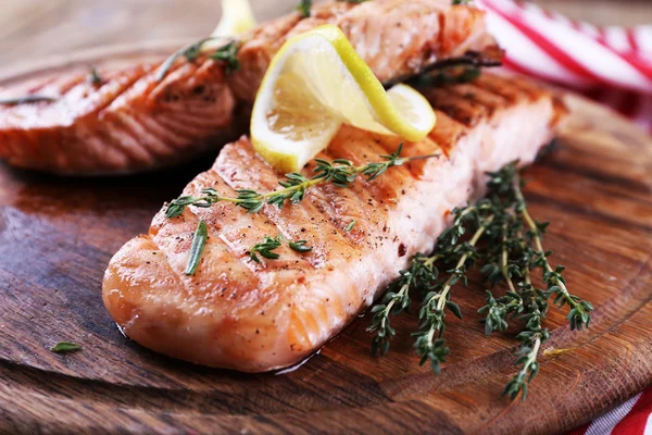 Grilled salmon on cutting board on wooden background — Stock Photo, Image