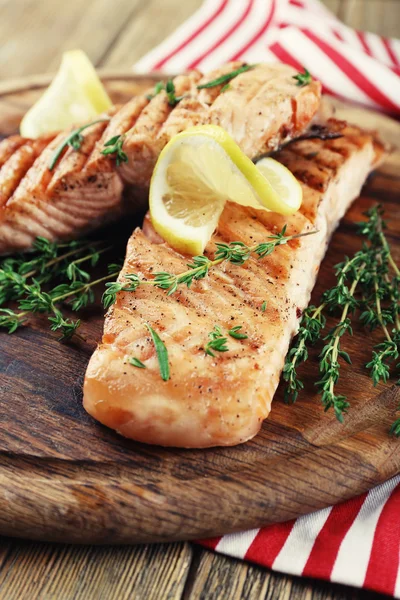 Salmón a la parrilla sobre tabla de cortar sobre fondo de madera —  Fotos de Stock