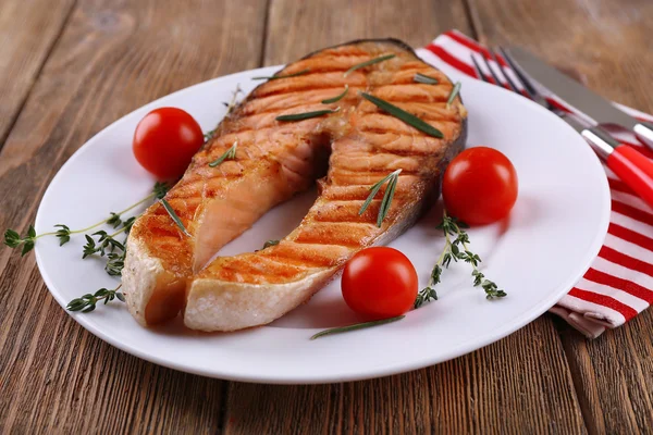 Salmon panggang dan sayuran di piring dengan latar belakang kayu — Stok Foto