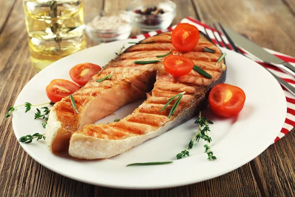 Grilled salmon and vegetables on plate on wooden background — Stock Photo, Image