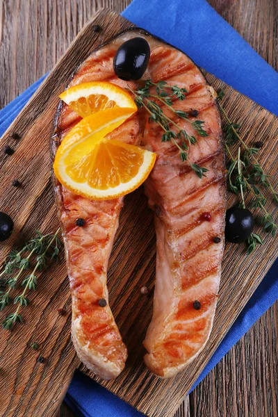 Gegrillter Lachs und Orangenscheiben auf Schneidebrett auf Holzgrund — Stockfoto