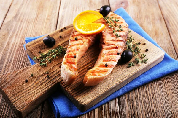 Grilled salmon  and orange slices on cutting board on wooden background — Stock Photo, Image