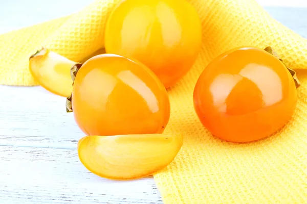 Ripe persimmons on color wooden background — Stock Photo, Image