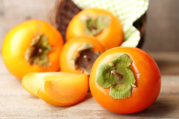 Ripe persimmons on wooden background — Stock Photo, Image