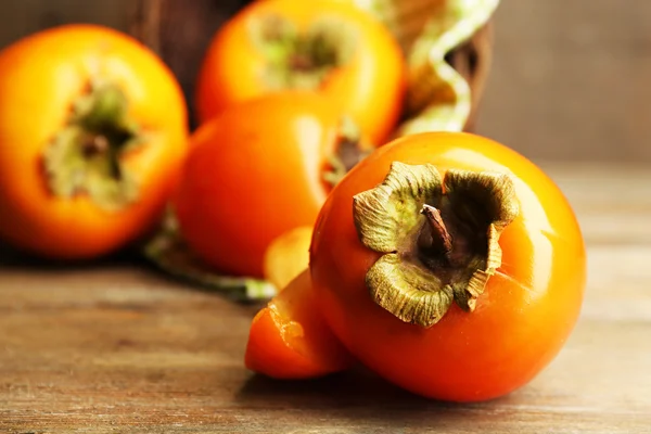 Ripe persimmons on wooden background — Stock Photo, Image