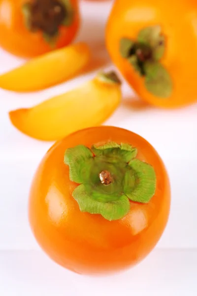 Ripe persimmons on color wooden background — Stock Photo, Image
