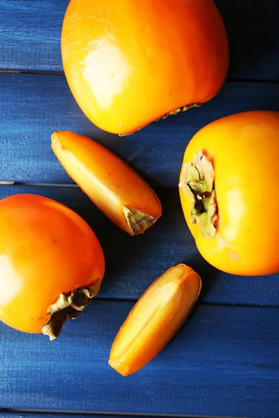 Ripe persimmons on color wooden background — Stock Photo, Image