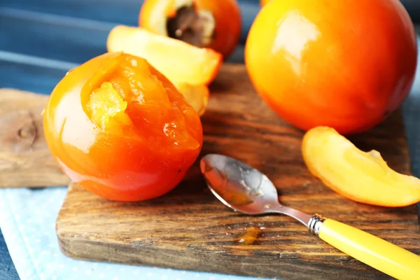 Ripe persimmons on cutting board,   close-up — Stock Photo, Image