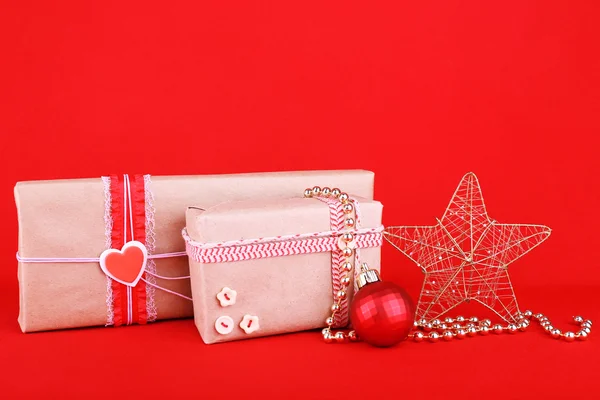 Schöne helle Geschenke und Weihnachtsdekoration auf rotem Hintergrund — Stockfoto