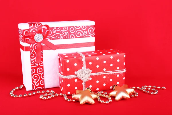 Hermosos regalos brillantes y decoración de Navidad sobre fondo rojo —  Fotos de Stock