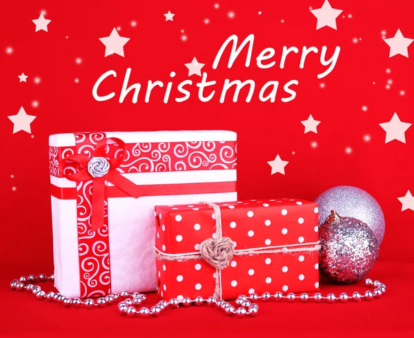 Belos presentes brilhantes e decoração de Natal no fundo vermelho — Fotografia de Stock