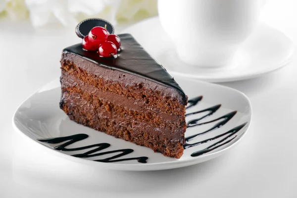 Delicious chocolate cake on plate on table on light background — Stock Photo, Image