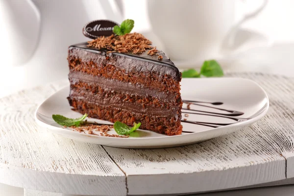 Delicious chocolate cake on plate on table on light background — Stock Photo, Image