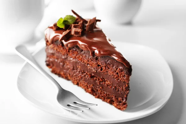 밝은 배경에 놓인 식탁 위에 놓인 맛있는 초콜릿 케이크 — 스톡 사진