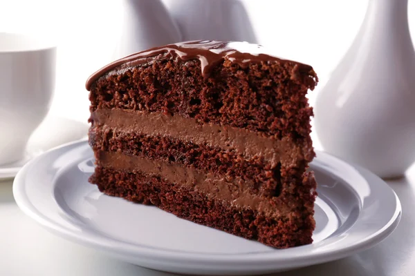 Delicious chocolate cake on plate on table on light background — Stock Photo, Image