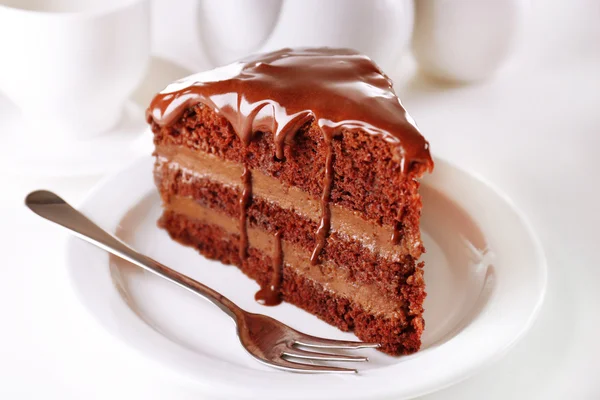 Köstlicher Schokoladenkuchen auf Teller auf Tisch vor hellem Hintergrund — Stockfoto