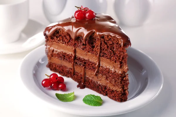 Delicioso bolo de chocolate na placa na mesa no fundo claro — Fotografia de Stock