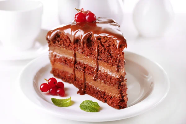 Delicioso bolo de chocolate na placa na mesa no fundo claro — Fotografia de Stock