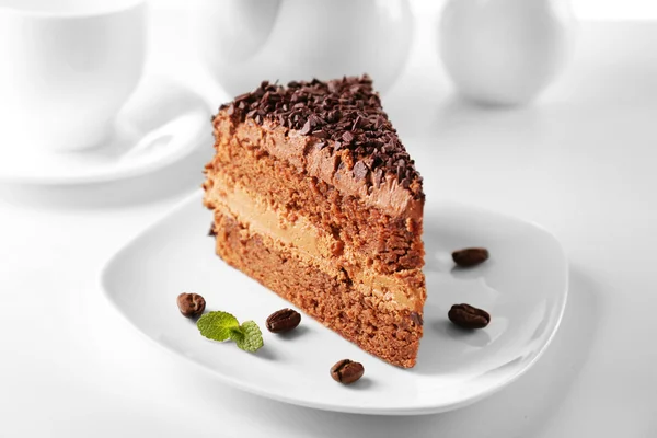 Delicioso bolo de chocolate na placa na mesa no fundo claro — Fotografia de Stock