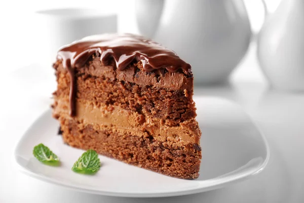 Delicioso bolo de chocolate na placa na mesa no fundo claro — Fotografia de Stock