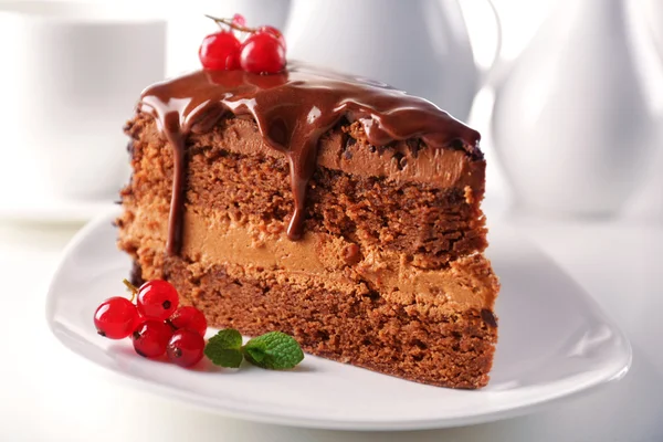 Delicioso bolo de chocolate na placa na mesa no fundo claro — Fotografia de Stock