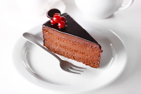 Köstlicher Schokoladenkuchen auf Teller auf Tisch vor hellem Hintergrund — Stockfoto