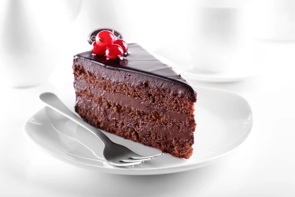 Delicioso pastel de chocolate en el plato en la mesa sobre fondo claro —  Fotos de Stock