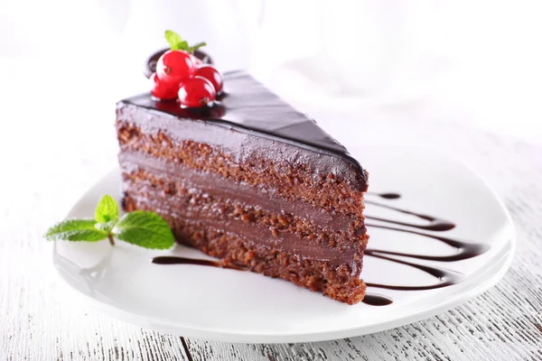 Delicioso pastel de chocolate en el plato en la mesa sobre fondo claro — Foto de Stock