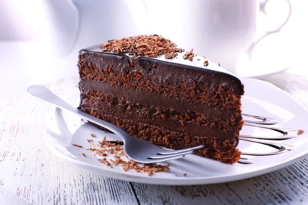 Köstlicher Schokoladenkuchen auf Teller auf Tisch vor hellem Hintergrund — Stockfoto