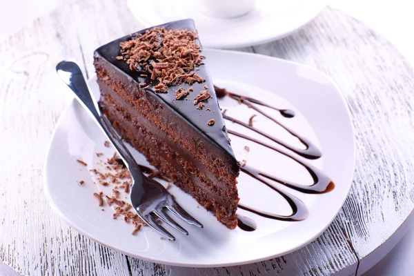 Delicioso pastel de chocolate en el plato en la mesa sobre fondo claro — Foto de Stock