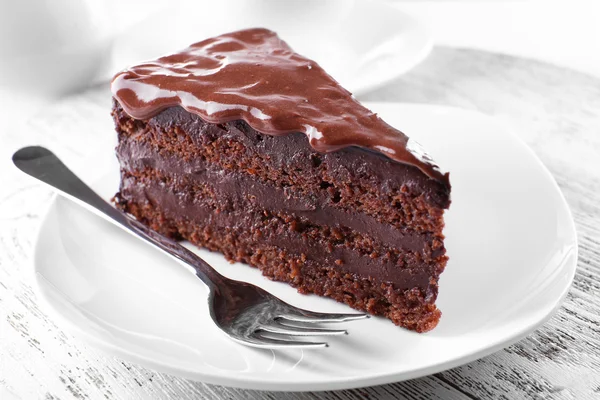 Köstlicher Schokoladenkuchen auf Teller auf Tisch vor hellem Hintergrund — Stockfoto