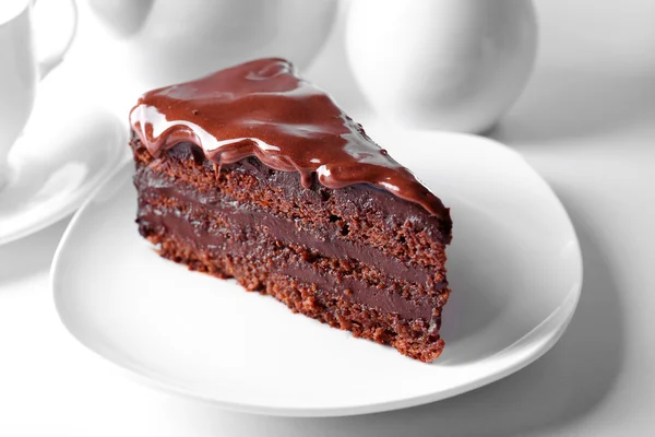 Delicious chocolate cake on plate on table on light background — Stock Photo, Image