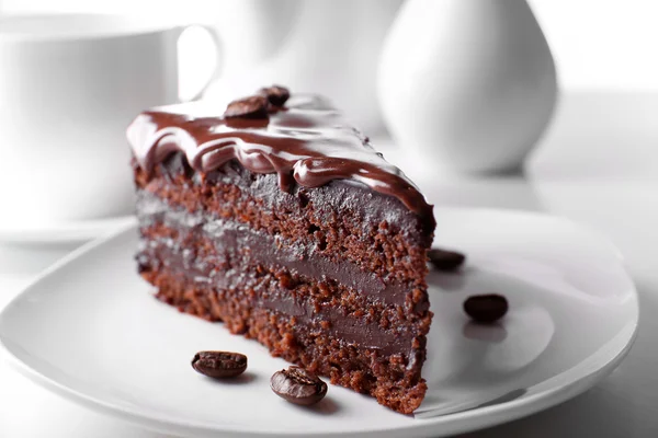 Delicioso bolo de chocolate na placa na mesa no fundo claro — Fotografia de Stock