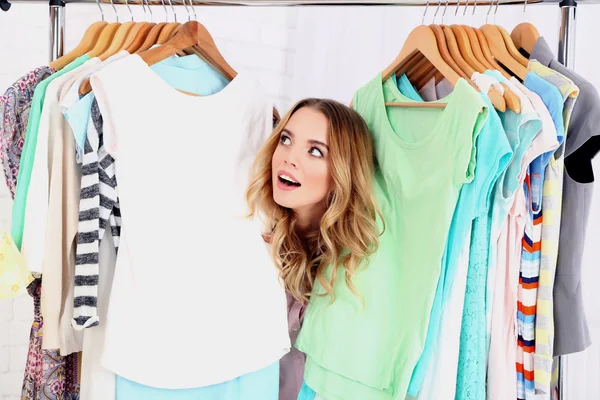 Mooie jonge vrouw in de buurt van rack met hangers — Stockfoto